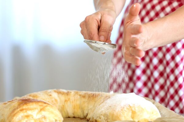 woman sprinkling powdered sugar on austrian strudel