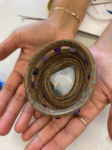 hand holding a handwoven Pine needle basket