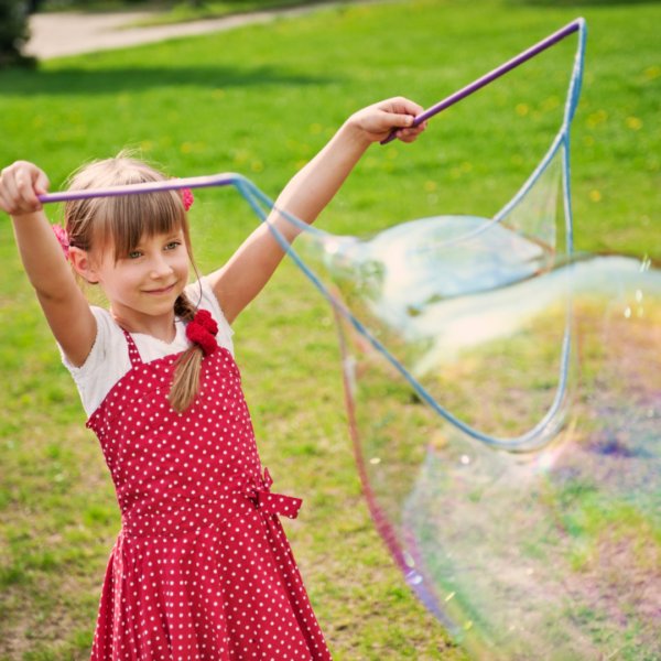 child creating large bubbles