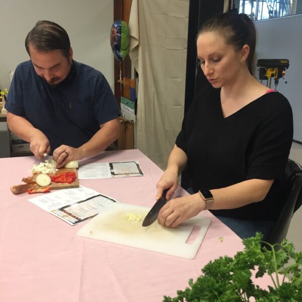 people sitting at a table cutting ingredients for an Italian meal