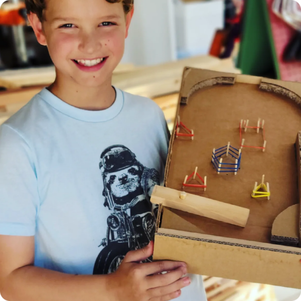 child holding handmade pinball machine STEAM project