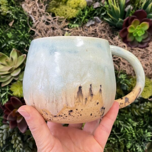 hand holding a ceramic glazed mug