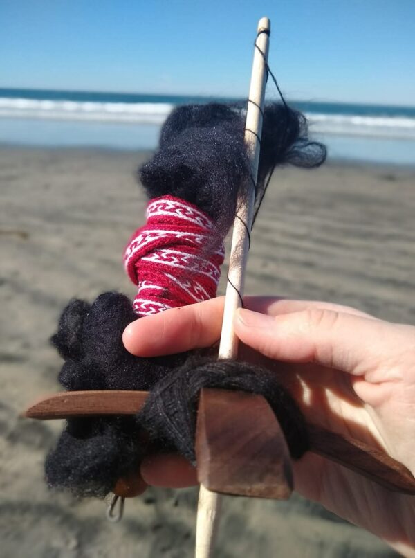 hand spinning wool on drop spindle with ocean in background
