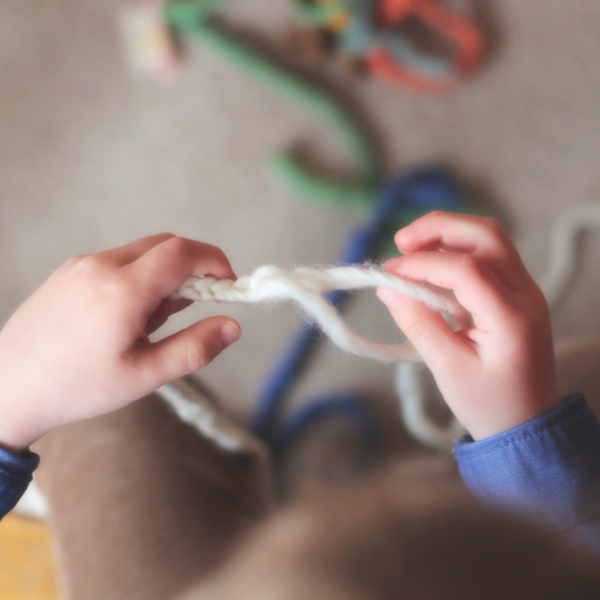 young child's hands working with yarn