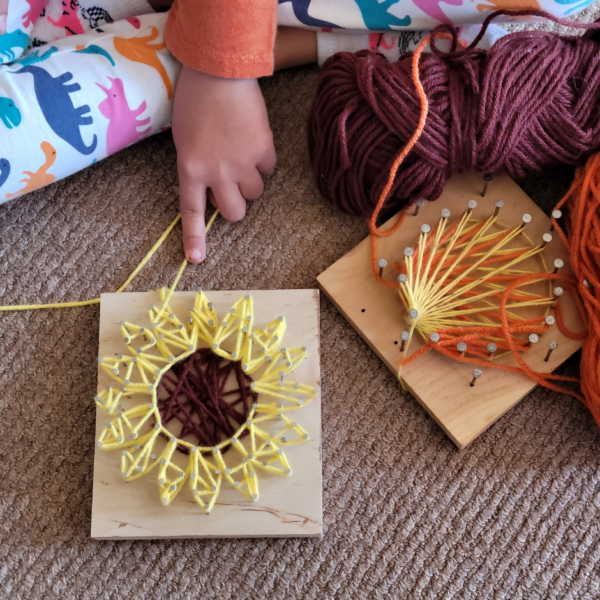 young child's hands working on string art