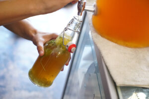 hand filling bottle with kombucha