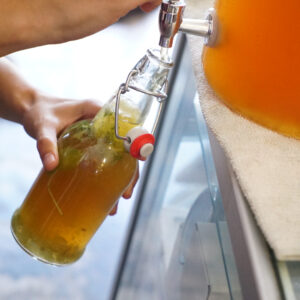 hand filling bottle with kombucha
