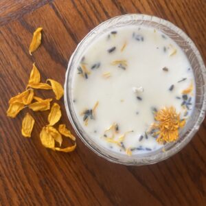 close up of candle with botanicals and flower petals