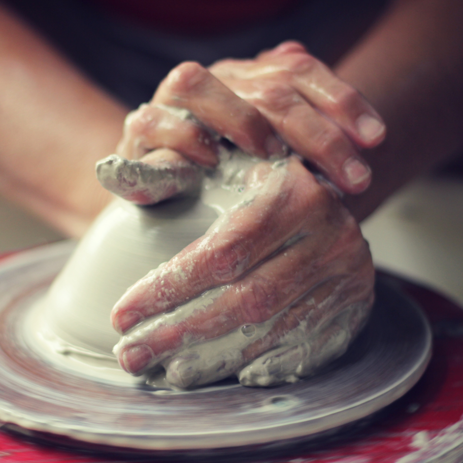 hands throwing and shaping clay on the ceramic wheel