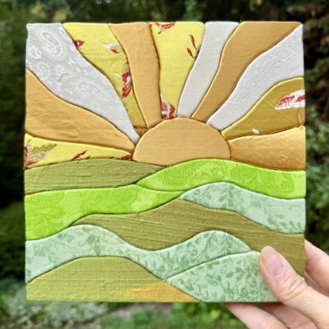 hand holding a kinusaiga sunshine over mountains fabric decoration