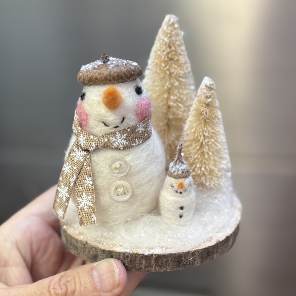 hand holding a small winter snowman scene